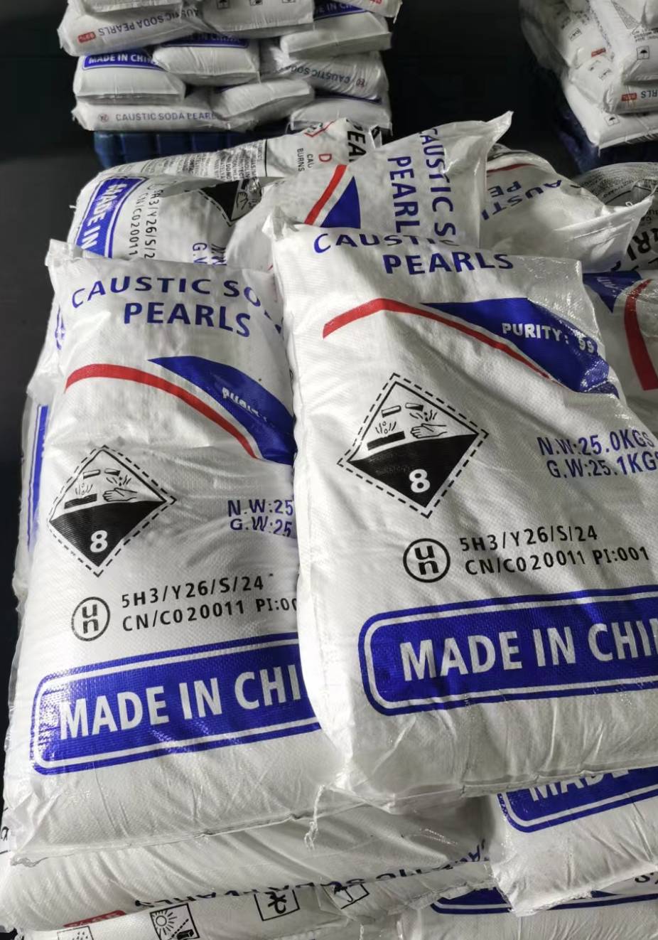 Bulk caustic soda pearls stacked in a warehouse for textile and leather manufacturers 